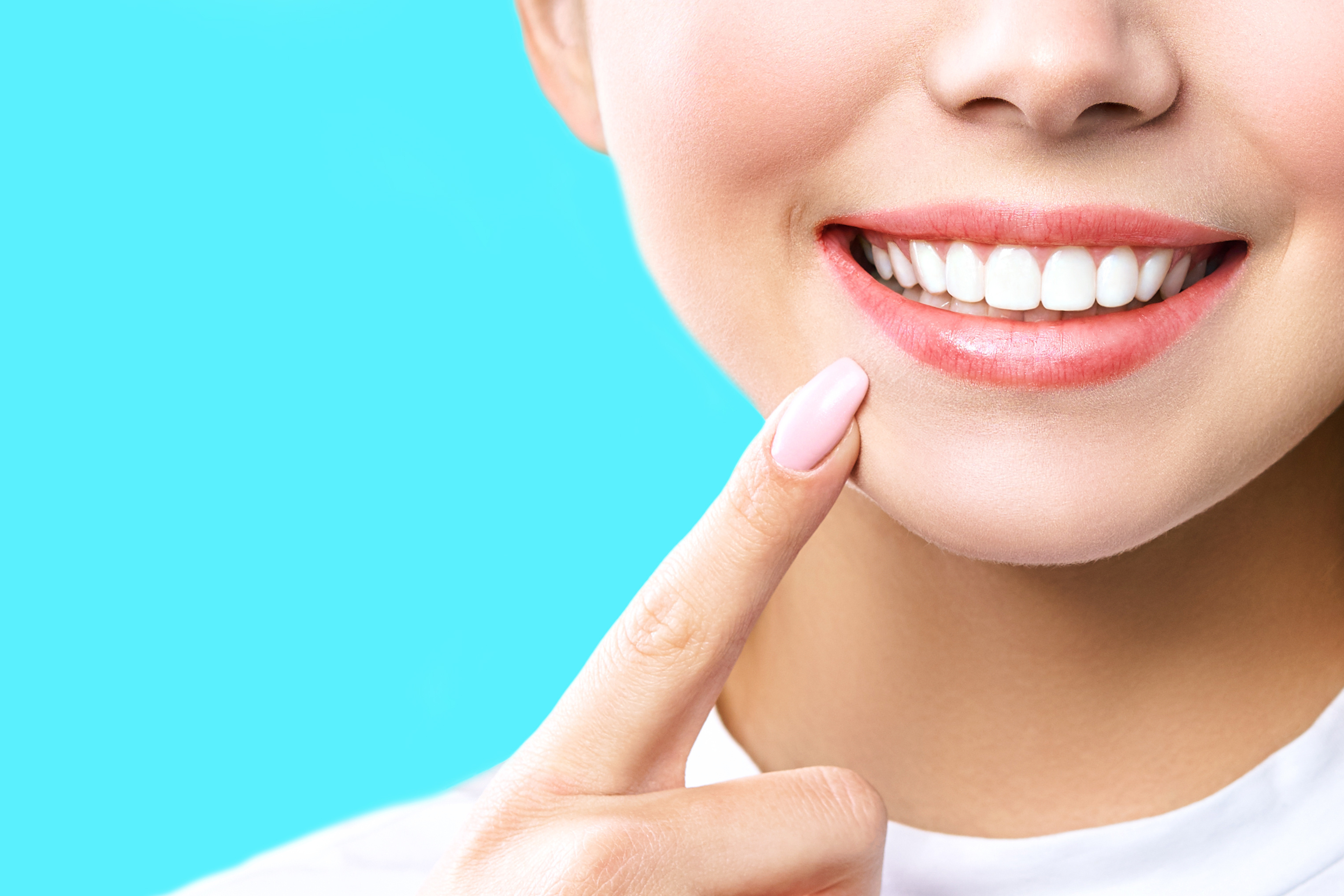 Close up shot of a woman pointing to her smiling mouth
