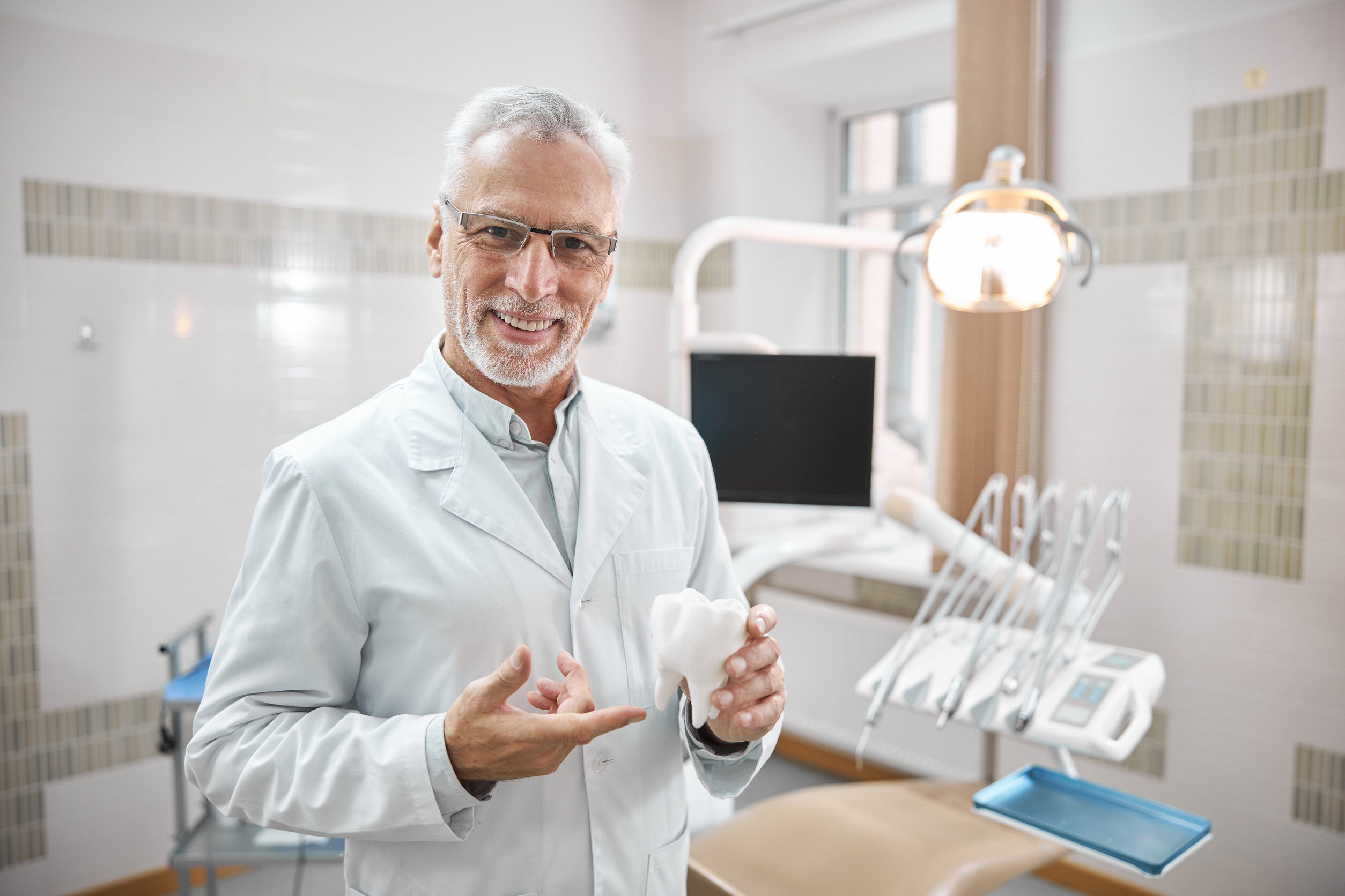 Image of a doctor in a white coat holding a model of a tooth