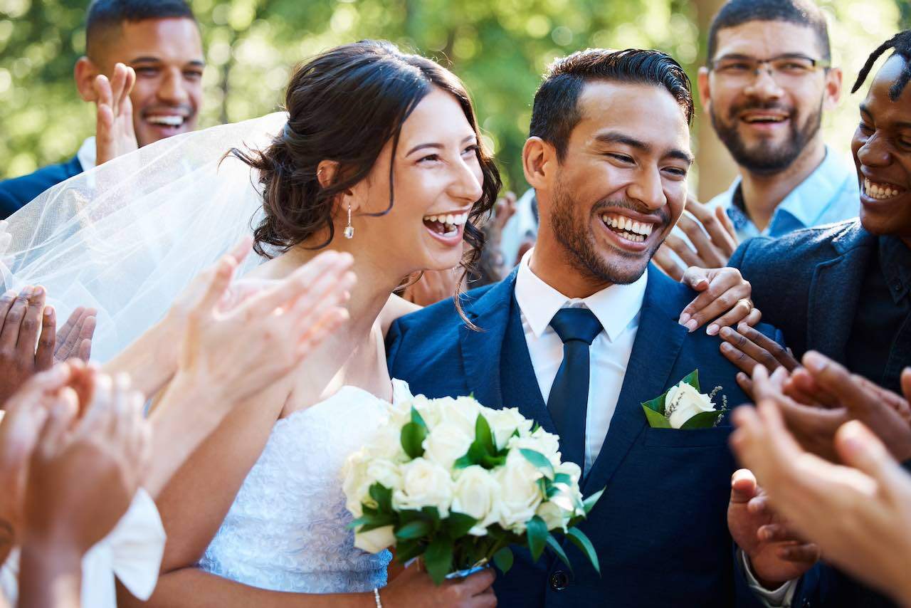 Photo of a bride and groom smiling wide and showing their straight white teeth